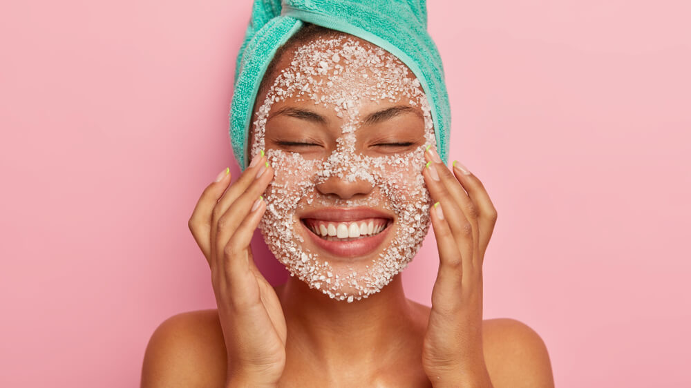 woman using facial scrub representing over exfoliation skin damage and skincare mistakes