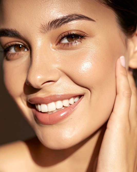 woman smiling with radiant glowing skin touching face gently representing clean beauty results